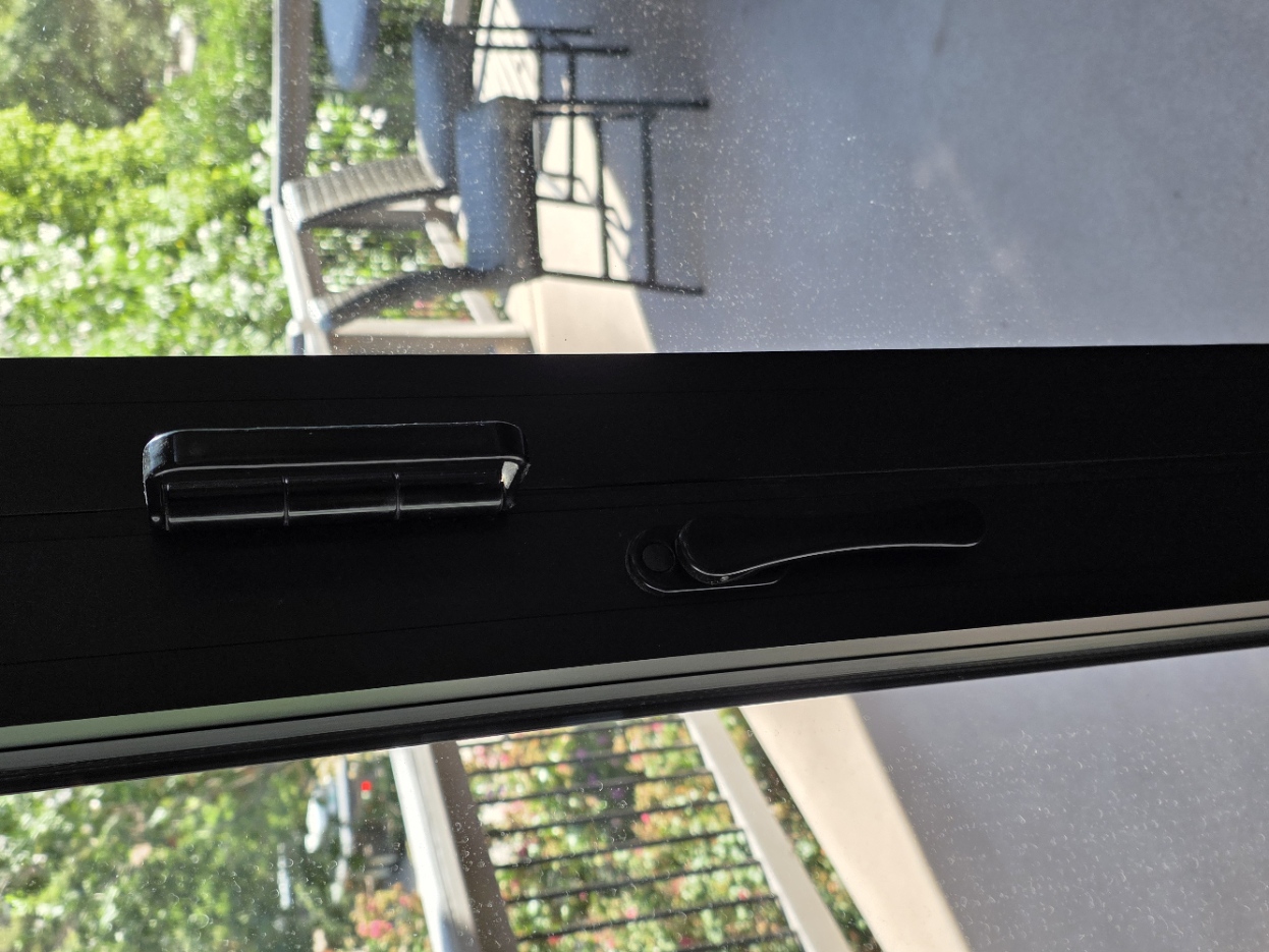 Close view of the slim vertical black release lever on an inner folding-glass-door panel.