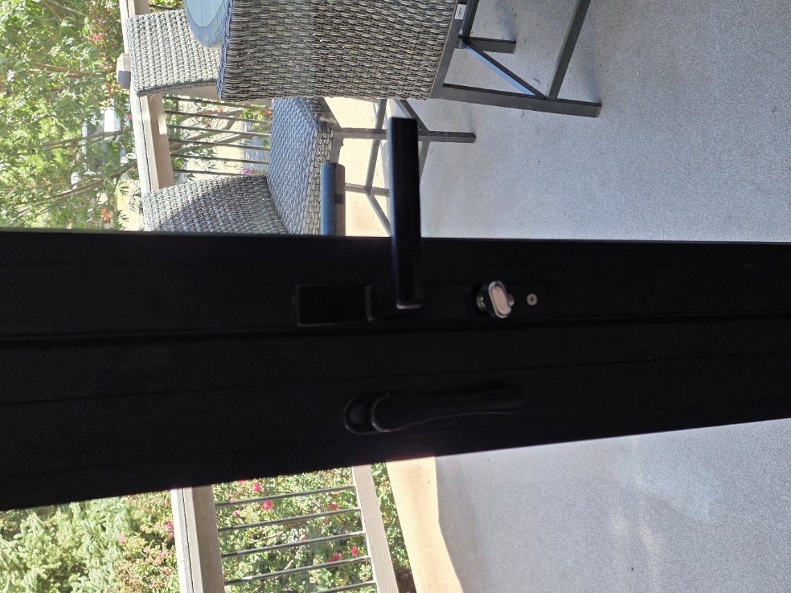 Closed glass doors with horizontal black main-door handle and small silver turn lock just below it.
